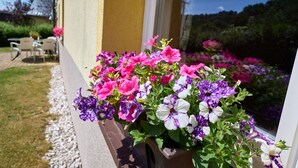 A window box with colorful flowers, a patio with chairs, and a view of a garden. - Nice apartment for 4 people with WIFI, TV, patio and pets allowed (Dvur Králové Nad Labem)