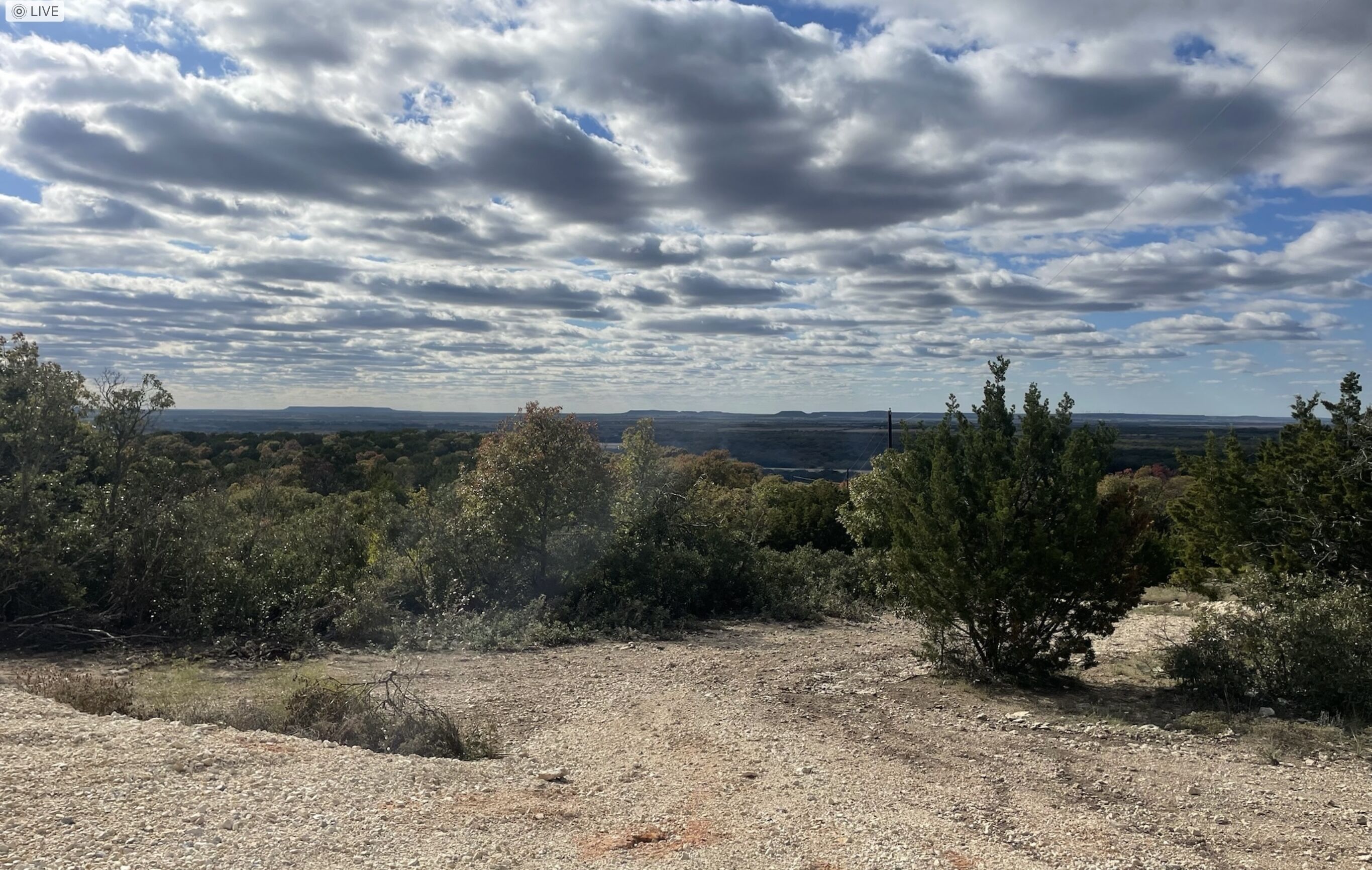Un paisaje natural con cielo despejado, colinas lejanas y vegetación escasa.
