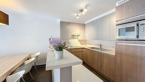 Eine moderne Küche mit Holzausstattung, einer weißen Arbeitsplatte und einer eingebauten Mikrowelle.