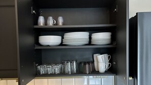 A kitchen with a black cabinet containing white plates, bowls, and cups.