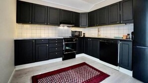 A modern kitchen with dark cabinets, a microwave, stove, and dishwasher.