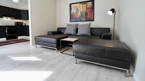 A modern living room with a sectional sofa, a small coffee table, and a painting on the wall.