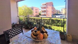 A balcony with a table set for a meal, potted plants, and a view of residential buildings. - Nice apartment for 3 people with WIFI, TV, terrace and pets allowed (Follonica)