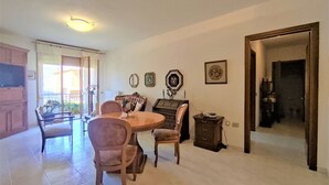 A dining area with a round table, chairs, and a cabinet. There is a door leading to another room. - Nice apartment for 3 people with WIFI, TV, terrace and pets allowed (Follonica)