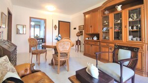 A living room with a dining table, chairs, a sofa, and a cabinet with glass doors. - Nice apartment for 3 people with WIFI, TV, terrace and pets allowed (Follonica)