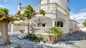 A white building with a stone facade, a balcony, and a staircase leading to the entrance. - Stunning private villa for 6 people with WIFI, TV, terrace and pets allowed (Empuriabrava)