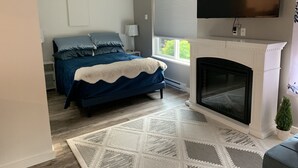 Une chambre à coucher avec un lit, une cheminée, une télévision et une fenêtre.