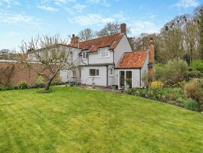 A two-story house with a sloped roof, a front garden, and a brick wall.
