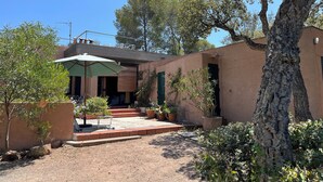 A rustic building with a patio area, outdoor seating, and potted plants.