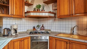A kitchen with wooden cabinets, a stainless steel stove, a built-in oven, a sink, and a coffee maker.