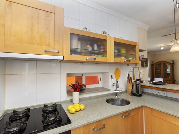 A kitchen with wooden cabinets, a stainless steel sink, and a gas stove.