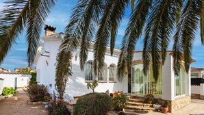 Un bâtiment blanc doté d’un patio, de palmiers et d’un petit jardin.