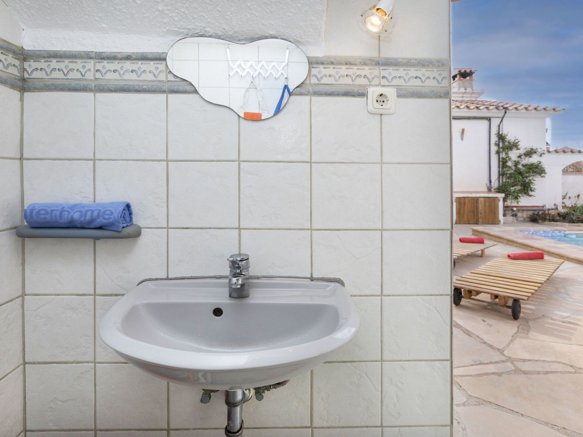 A bathroom with a white sink, a towel rack, and a mirror.
