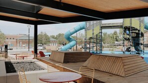 An outdoor seating area with tables and chairs, a blue slide, and a climbing structure. - Cozy 3BR Home with AC, Hot Tub & Walkable Restaurants (Wheat Ridge)