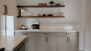 A kitchen with white tiles, a coffee maker, and wooden shelves. - Cozy 3BR Home with AC, Hot Tub & Walkable Restaurants (Wheat Ridge)