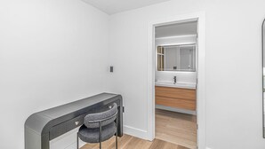 A modern bathroom with a vanity, mirror, and a chair. - Queen Suite/Fifth and Ocean (Myrtle  Beach)