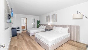 A hotel room with two beds, a desk, a chair, a mirror, and a plant. - Queen Suite/Fifth and Ocean (Myrtle  Beach)