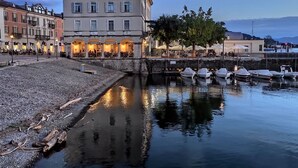 Ein Gebäude am Wasser mit vielen Fenstern und einer gepflasterten Fläche davor.