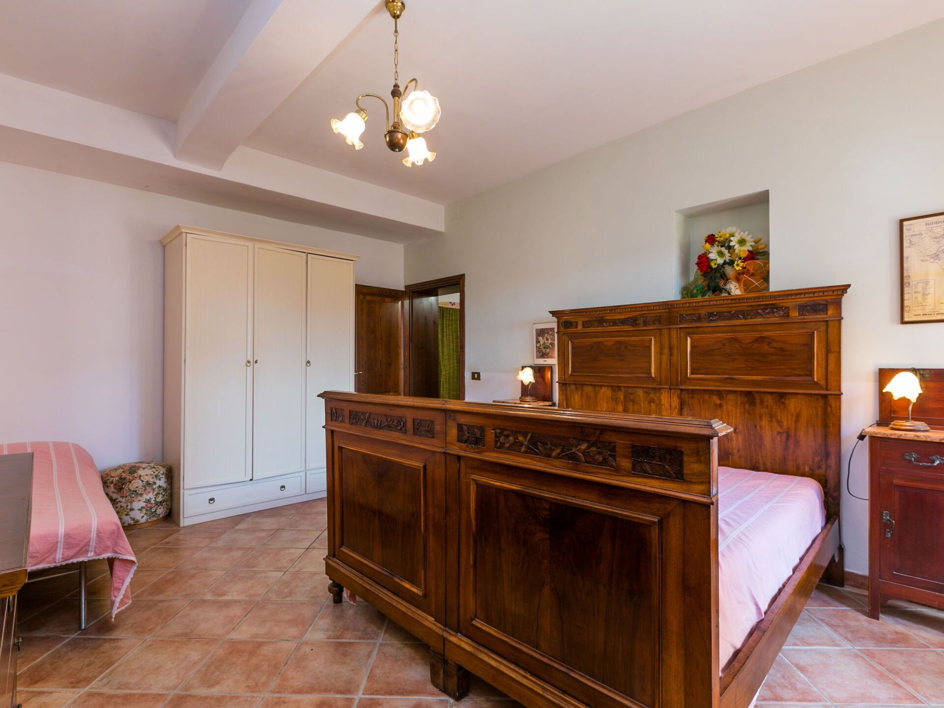 Un dormitorio con cama de madera, un armario, un escritorio y una araña.