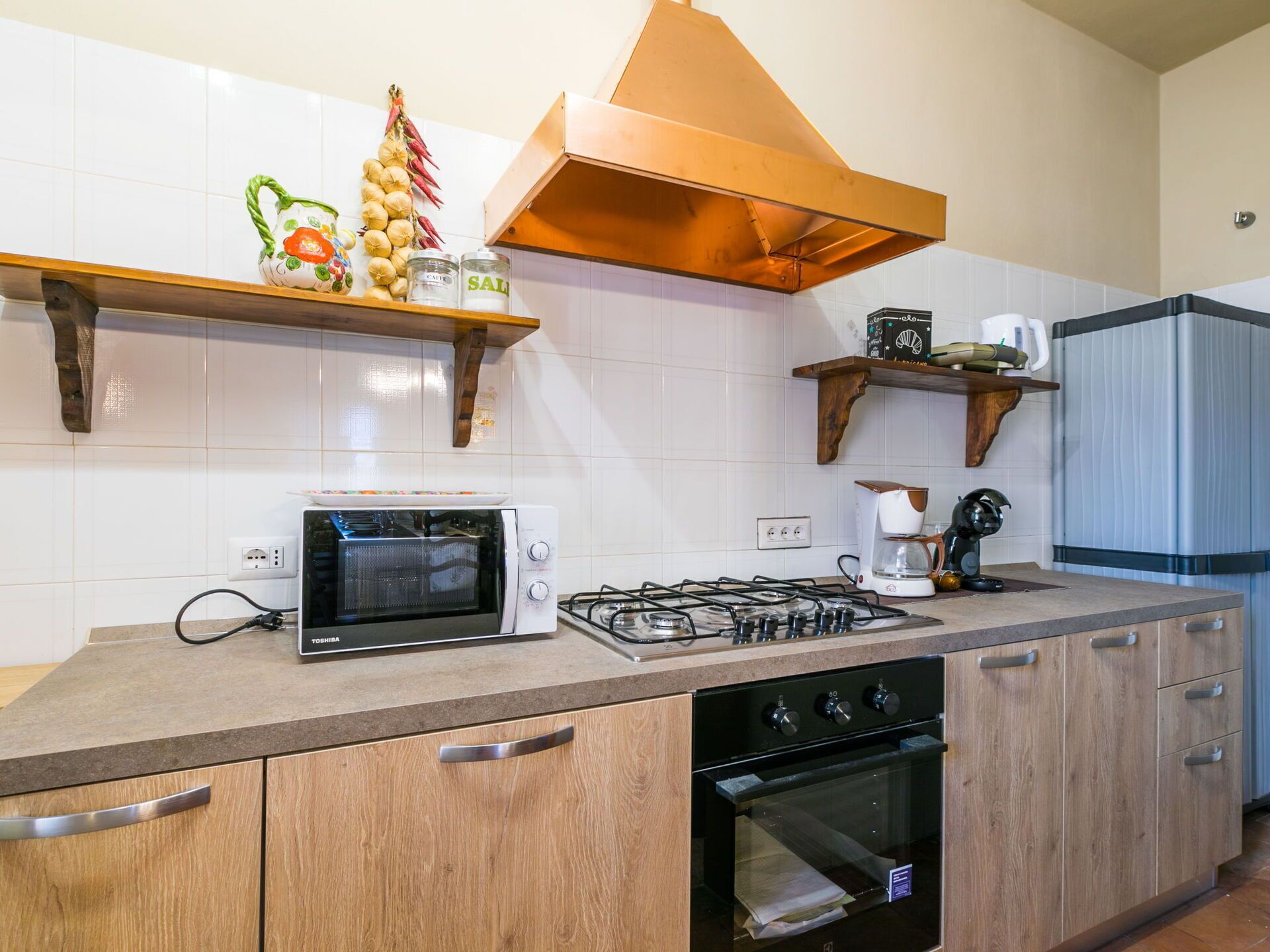 Une cuisine équipée d’un four encastré, d’une cuisinière, d’un four à micro-ondes et de meubles de rangement en bois.