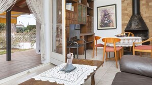 A cozy living room with a fireplace, a television, and a dining area with a table and chairs. - Wonderful  villa for 6 people with WIFI and TV (L'escala)