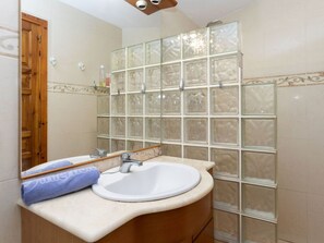 A bathroom with a white sink, wooden vanity, and a glass shower enclosure. - Wonderful  villa for 6 people with WIFI and TV (L'escala)