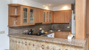 A kitchen with granite countertops, wooden cabinets, and a built-in stove. - Wonderful  villa for 6 people with WIFI and TV (L'escala)