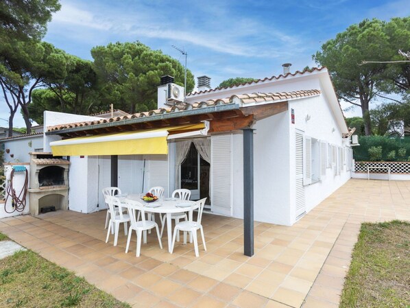 A white house with a tiled patio, outdoor seating, and a pizza oven. - Wonderful  villa for 6 people with WIFI and TV (L'escala)