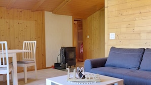 Ein gemütliches Zimmer mit Holzvertäfelung, einer Couch, einem Tisch und einem kleinen Kamin.