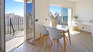 Un apartamento moderno con balcón, zona de comedor con sillas y mesa, y vistas a la ciudad y al mar.