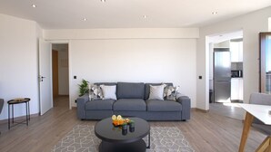 Un salón moderno con un sofá gris, una mesa de centro redonda y una alfombra con estampado geométrico.