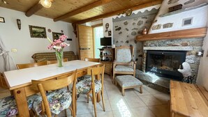A cozy dining area with a wooden table and chairs, a vase of flowers, and a stone fireplace. - Beautiful private villa for 3 guests with WIFI, TV, terrace and pets allowed (Verceia)