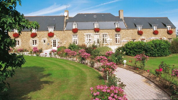 A stone building with multiple windows and flower boxes. - Nice apartment for 5 guests with WIFI, pool, TV and terrace (Saint-jouan-des-guérets)