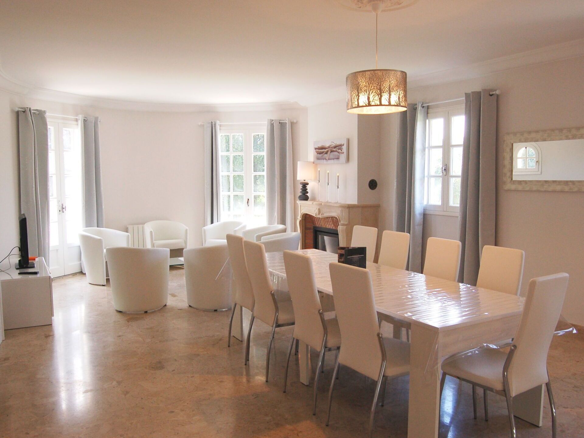 A spacious dining area with a large table and multiple chairs, a fireplace, and a chandelier.