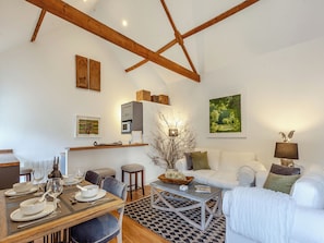 A well-lit living room with a dining area, white furniture, and a wooden ceiling structure.