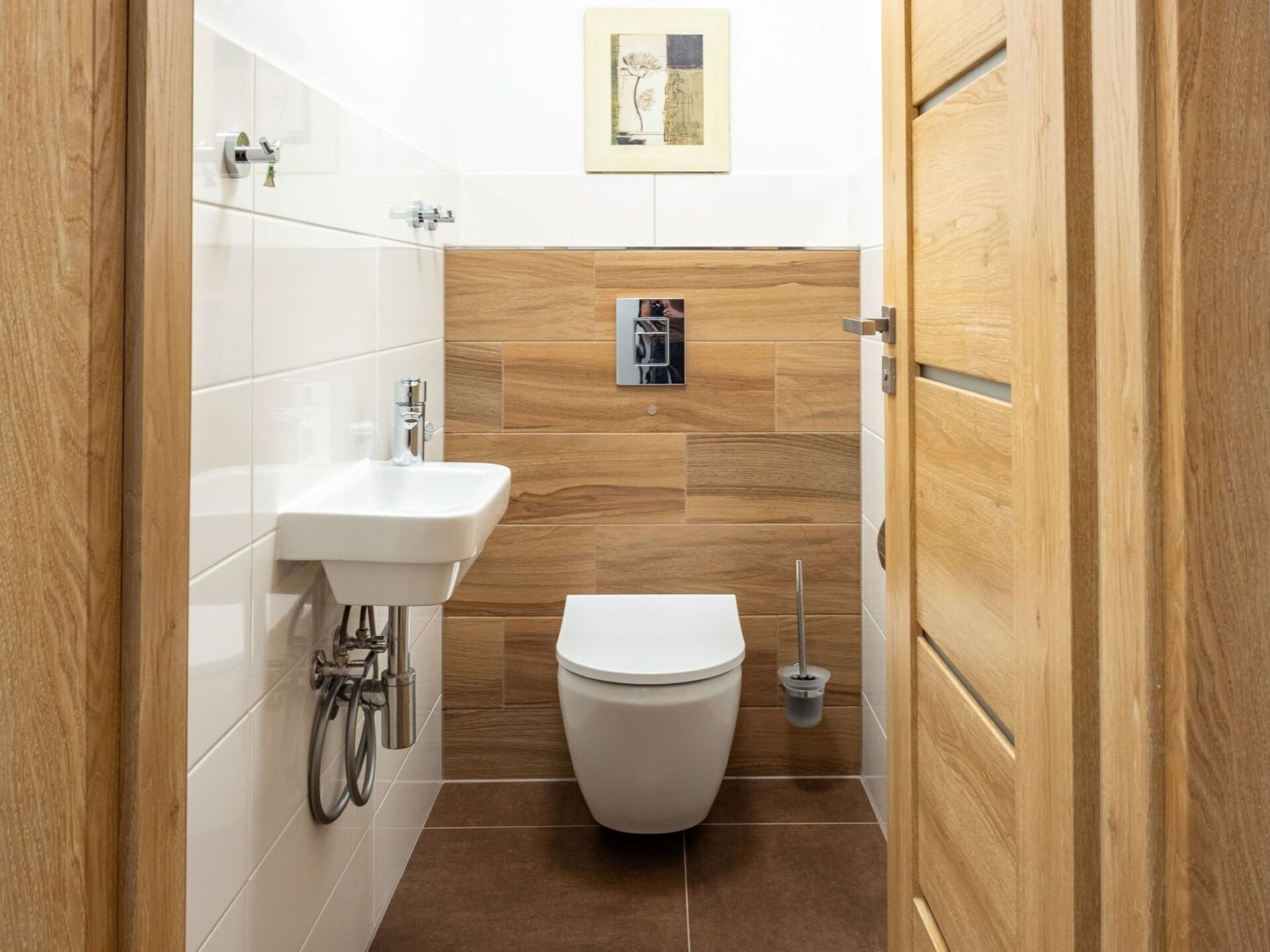 Un baño pequeño con lavamanos blanco, inodoro y tocador de madera.