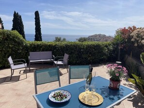 A patio with a table set for two, overlooking a coastal view.