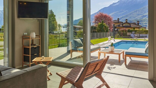 Un saló modern amb una àmplia porta corredissa de vidre que dona a una zona de piscina amb vista a la muntanya.