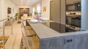 Eine moderne Küche mit einer zentralen Kochinsel, Barhocker, Backofen und Mikrowelle.
