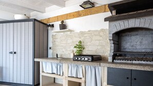 Una cocina con pared de piedra, una parrilla empotrada y un armario de madera.