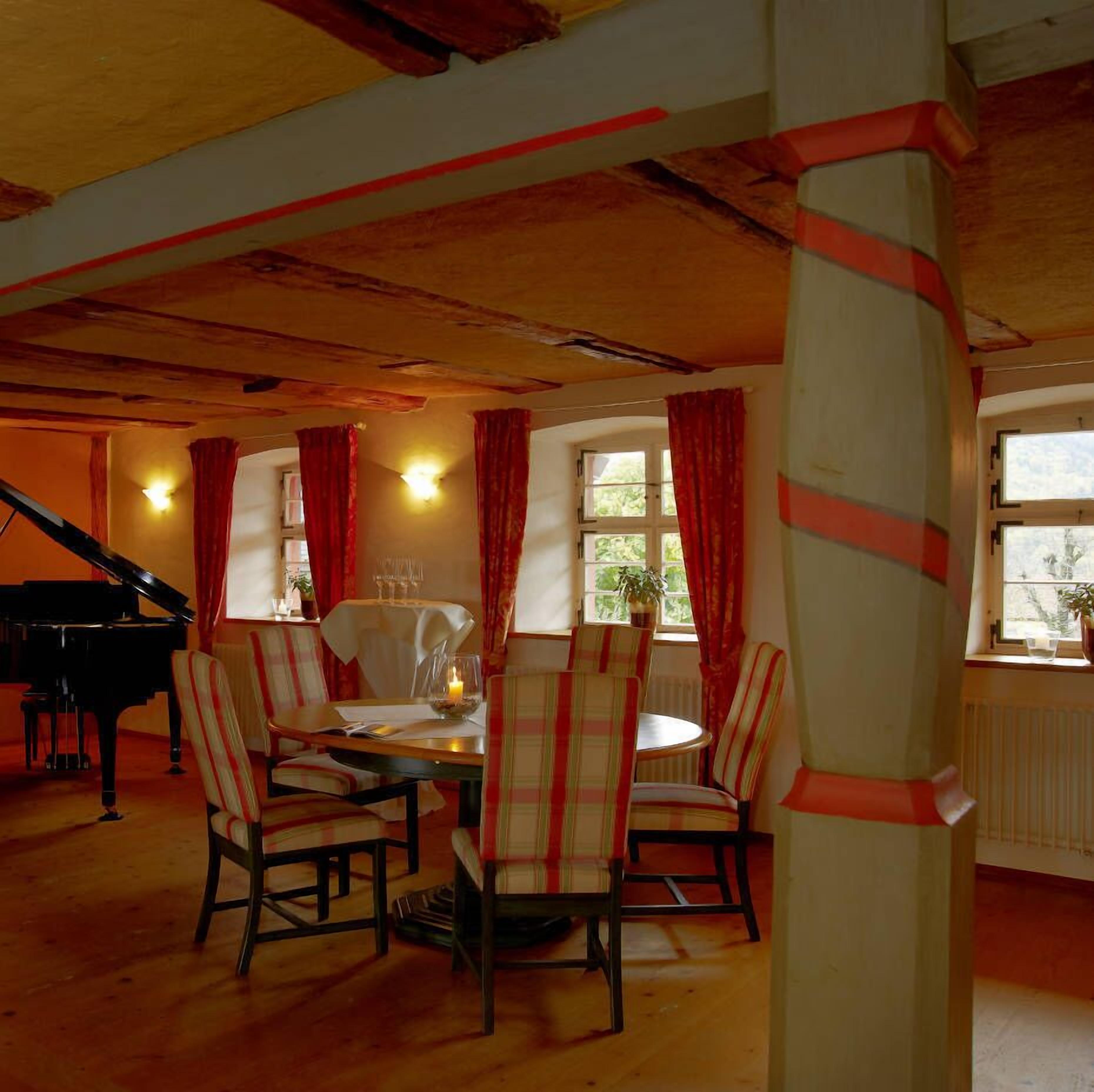 Comedor con un piano, sillas a rayas y una mesa preparada para dos.
