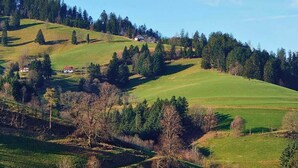 A rural landscape with rolling hills, a farmhouse, and scattered trees. - Gasthaus zum Raben (Horben)