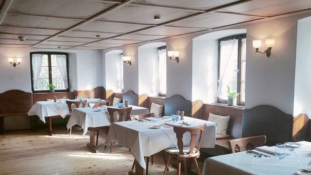 A dining area with wooden floors, white tablecloths, and wooden chairs. - Gasthaus zum Raben (Horben)