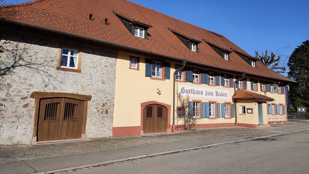 A traditional building with a tiled roof, stone walls, and wooden doors.