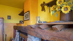 Un interior rústico con chimenea de piedra, vigas de madera y una estantería con girasoles.