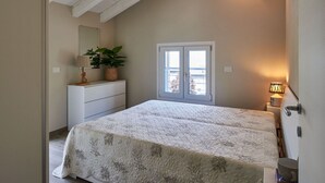 Une chambre à coucher comprenant un lit, une commode, des plantes en pot, une fenêtre et un climatiseur fixé au mur.
