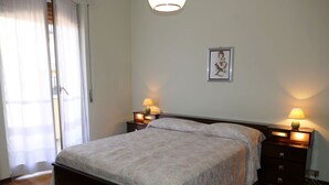 Een slaapkamer met een bed, twee nachtkastjes met lampen, een schilderij aan de muur en een schuifdeur.