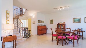 A spacious living area with a staircase, a dining table with chairs, and a wooden cabinet. - Beautiful private villa for 5 guests with TV and patio (Camaiore)