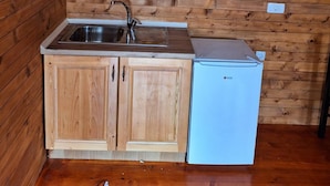 A compact kitchen with wooden cabinets, a sink, and a small refrigerator. - Zenith Campsite Apartments (Niksic)