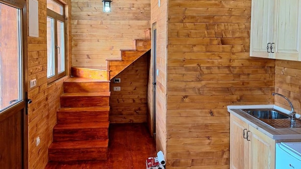 A wooden interior with a kitchen area, wooden stairs, and a small window. - Zenith Campsite Apartments (Niksic)